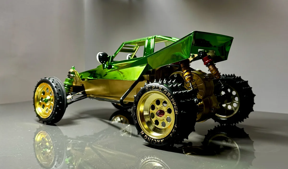 Green and gold radio-controlled buggy photographed on a reflective surface